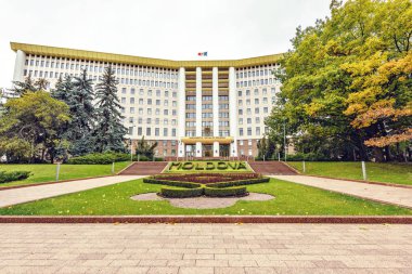 Bulutlu bir günde ülkenin parlamentosu geniş atış. Negatif kopya alanı, metin için yer. Küçük bahçe önünde çiçeklenir. Kişinev, Moldova