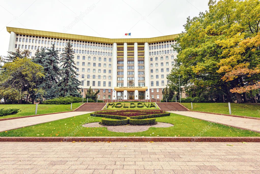 Wide shot of the country parliament in a cloudy day. Negative copy space, place for text. Flowers in little garden in front. Chisinau, Moldova