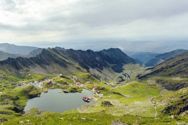 Balea Gölü ve Fagaras Dağları, Romanya'da serpantin yol toplayan. Bulutlu gökyüzü. Geniş çekim