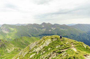 Balea Gölü yakınındaki bir tepe tırmanma, dağlarda İnceleme adam. Bulutlu gökyüzü arka plan üzerinde. Metin için yer. Fagaras, Romanya