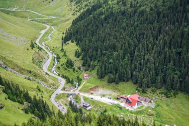 Transfagarasan dolambaçlı yol ve chalet üstten. Road yakınındaki su akışı. Yeşil orman arka plan üzerinde. Fagaras dağlar, Romanya