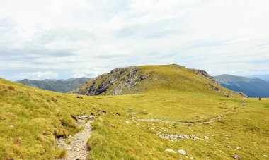 Bulutlu bir günde Paltinului eyer. Yeşil çim ve parlak gökyüzü. Fagaras dağlar, Romanya