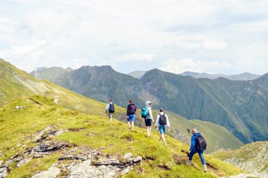 Arkadaşlar Fagaras Dağları'nda bir yol üzerinde hiking. Parlak gökyüzü bulutlu arka plan üzerinde. Romanya
