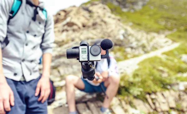 Blogger holding camera on monopod, filming in Fagaras Mountains. Close-up shot. Place for text. Romania