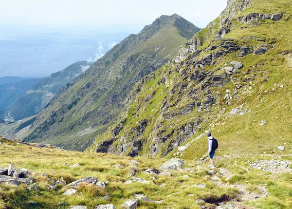 Lonely tourist exploring Fagaras Mountains near Balea Lake. Blue sky on background. Romania beauties