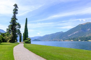 Como Gölü kıyısındaki yol ve çim sahada. Dağlar ve arka plan üzerinde şehirler. Bellagio, İtalya