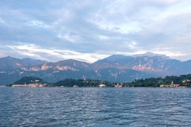 Kırmızı güneş hatta dağlar Bellagio şehir üzerinde. Bulutlu gökyüzü. Lenno, İtalya'dan görünüm