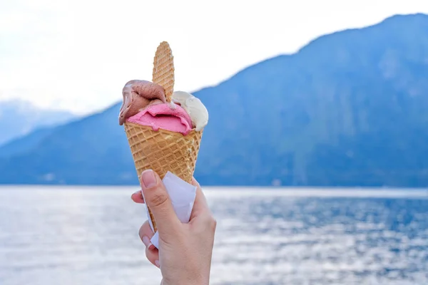 女性の手持ち株アイスクリームのワッフル コモ湖と夕日の背景に山です レンノ イタリア — ストック写真