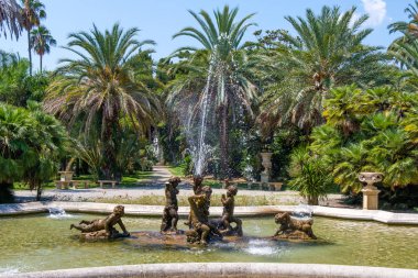Çeşme çocuklu nobel bahçe park heykeller. Yeşil ağaçlar ve zemin üzerine mavi gökyüzü. Sanremo, İtalya