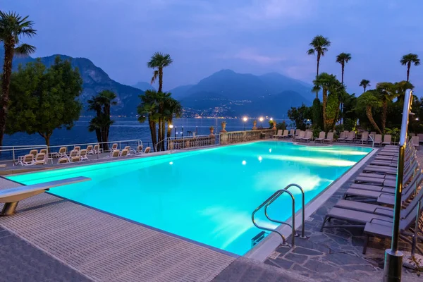 Empty hotel pool at night. Lake Como, palms and mountains on background. Villa Serbelloni. Bellagio, Italy