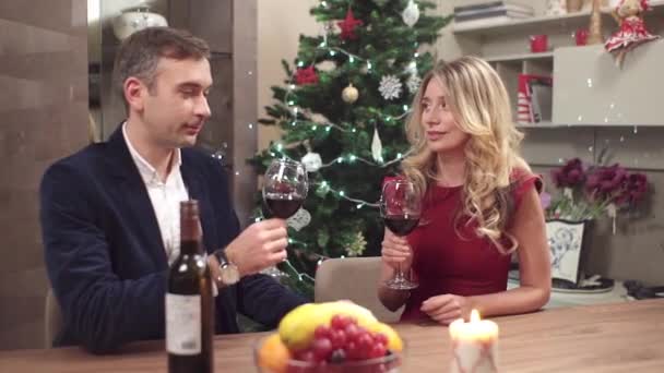 白色高加索年轻夫妇在一个浪漫的圣诞晚宴与葡萄酒 红色连衣裙 节日装饰品和礼品 — 图库视频影像