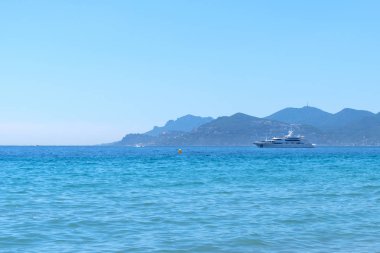 Cannes beach yakınındaki lüks yat. Backgorund dağlarında. Güneşli bir gün büyük bir gemide güneşlenin. Sakin mavi su
