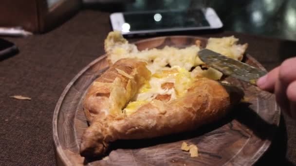 ジョージアン様式のレストランで 伝統的な焼きたての卵とチーズのパンを食べて Khachapuri を閉じる — ストック動画