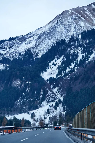 Highway with car riding on it. Huge mountains covered with snow on background. Innsbruck, Austria