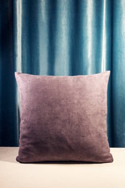 Mor yastık ayakta dikey olarak bir tablo. Mavi kadife arka plan. Yumuşak dekoratif süsler. Sıcak bakmak