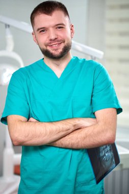 Xray elinde tutan ve gülümseyen beyaz erkek diş hekimi