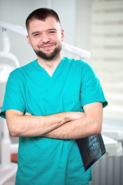 Xray elinde tutan ve gülümseyen beyaz erkek diş hekimi
