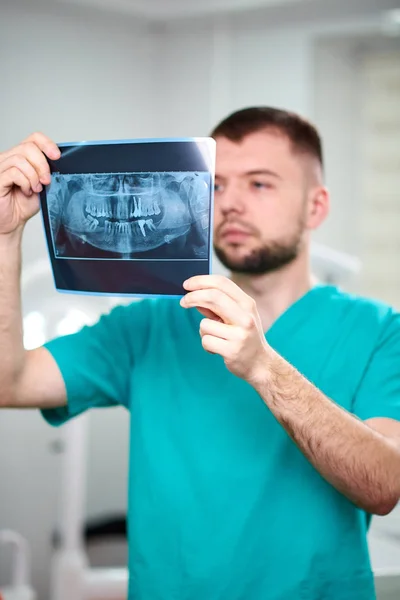 Caucásico dentista masculino sosteniendo rayos X en las manos y sonriendo — Foto de Stock