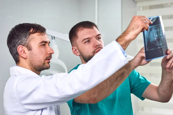 Dos dentistas masculinos caucásicos analizando rayos X — Foto de Stock