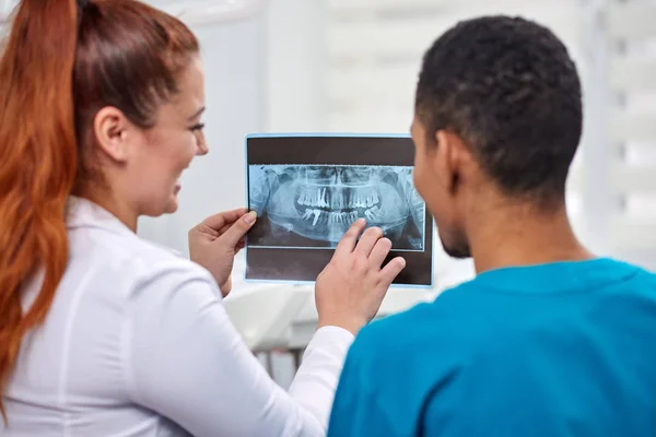 Dentista femenina caucásica explicando a un novato africano radiografía — Foto de Stock