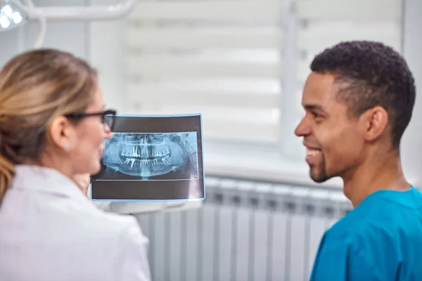 Dentista femenina caucásica explicando a un novato africano radiografía — Foto de Stock