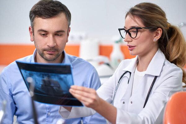 Caucasian female dentist explaining to male patient the x-ray