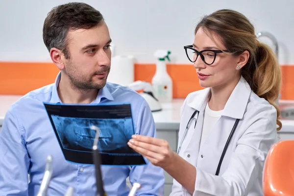 Dentiste caucasienne expliquant au patient masculin la radiographie — Photo