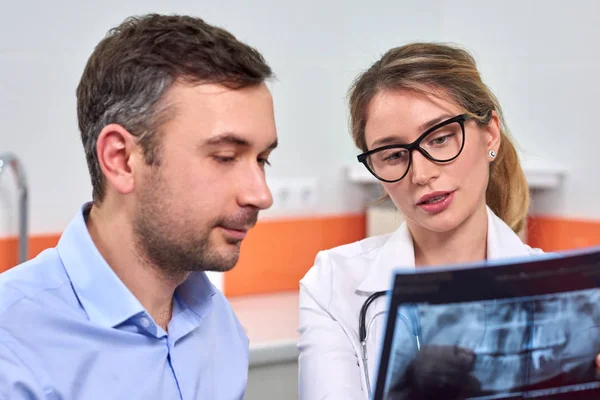 Dentista mujer caucásica explicando al paciente masculino la radiografía — Foto de Stock