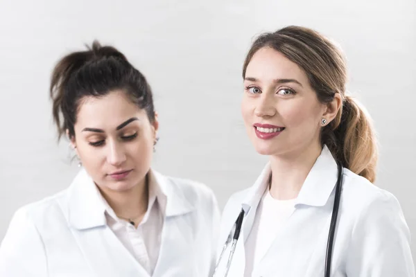 Deux assistantes vêtues de manteaux blancs se parlent au centre de dentisterie — Photo