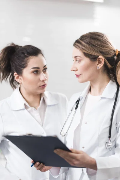 Deux assistantes vêtues de manteaux blancs se parlent au centre de dentisterie — Photo