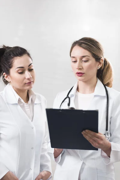 Deux assistantes vêtues de manteaux blancs se parlent au centre de dentisterie — Photo