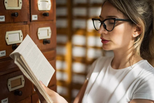 Blonde woman reading a book in public library