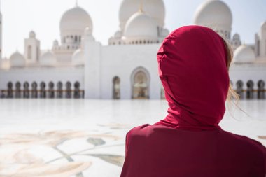 Abu Dabi Camii'nde bir kadın. Bae'deki Şeyh Zayed Ulu Camii'ne bakan kırmızı bir başörtüsü takıyor. Güneşli gün, güzel mimari manzarası