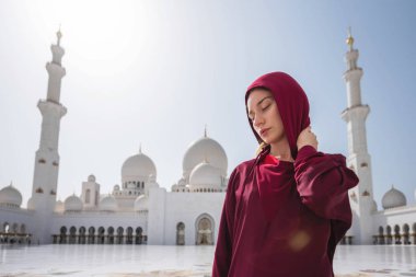 Abu Dabi Camii'nde bir kadın. Bae'deki Şeyh Zayed Ulu Camii'ne bakan kırmızı bir başörtüsü takıyor. Güneşli gün, güzel mimari manzarası