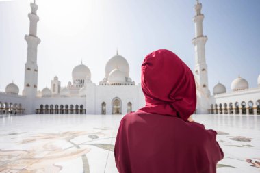 Abu Dabi Camii'nde bir kadın. Bae'deki Şeyh Zayed Ulu Camii'ne bakan kırmızı bir başörtüsü takıyor. Güneşli gün, güzel mimari manzarası