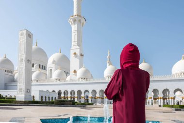 Abu Dabi Camii'nde bir kadın. Bae'deki Şeyh Zayed Ulu Camii'ne bakan kırmızı bir başörtüsü takıyor. Güneşli gün, güzel mimari manzarası