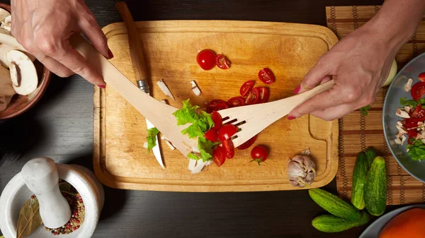 Nő keverés egészséges saláta a konyhában, fa edények — Stock Fotó