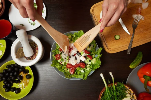 Накладний знімок жіночих рук, змішуючи здоровий грецький салат — стокове фото