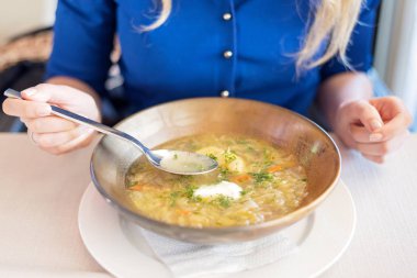 Kahverengi tabakta ördek çorbası yiyen kadın