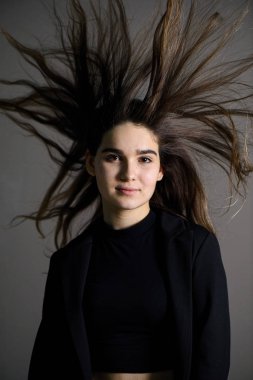 Gri arka planda poz veren kahverengi saçlı genç beyaz kız