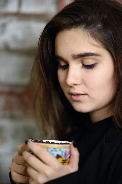 Young caucasian girl drinking from coffee cup full of beans — Stock Photo, Image