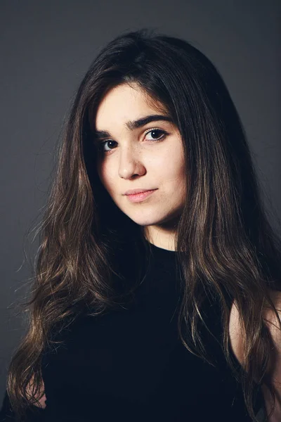 Young caucasian girl with brown hair posing on grey background — Stock Photo, Image