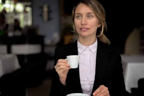 Happy young blonde woman drinking coffee