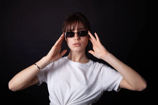 Kaukasiska flicka i vit skjorta med svarta solglasögon poserar i studion — Stockfoto