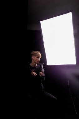 Softbox arka planda poz veren genç bir yetişkinin sahne arkası fotoğrafı