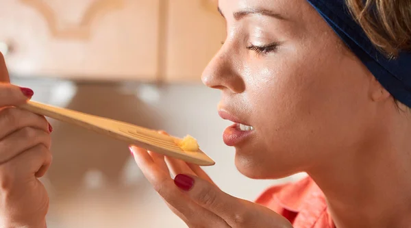 Gambar close-up seorang wanita mencicipi hidangan dari spo pencampuran kayu — Stok Foto