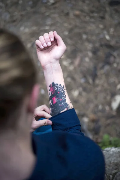 Homem com cabelo amarrado olhando para sua tatuagem no braço direito — Fotografia de Stock