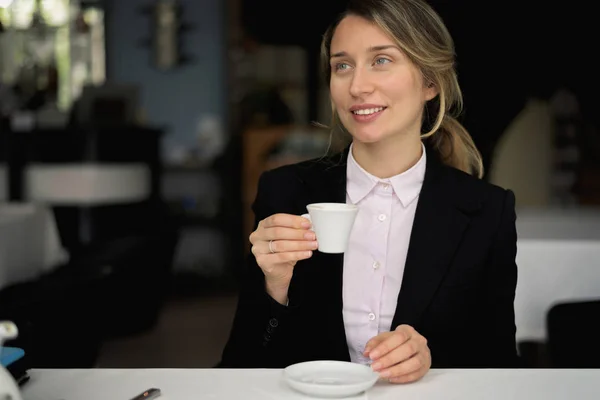 Happy young blonde woman drinking coffee