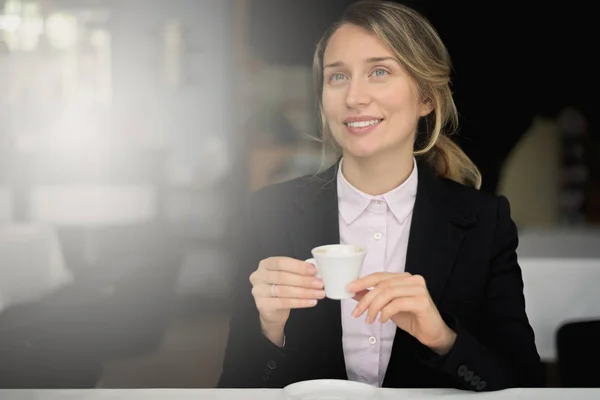 Happy young blonde woman drinking coffee
