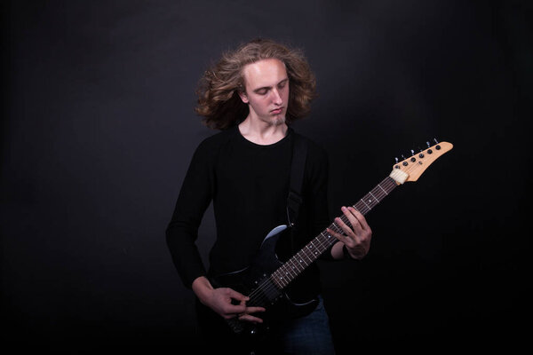 Young caucasian adult playing guitar in the studio